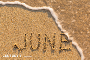 Picture of the word JUNE at the beach with a wave starting to wash over it